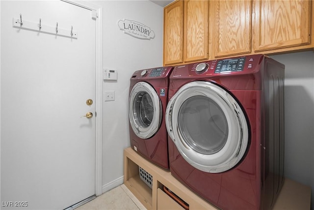 clothes washing area featuring washing machine and dryer, light tile patterned flooring, and cabinet space