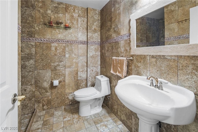 half bathroom with toilet, tile walls, and a sink