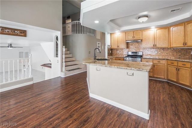 kitchen with stainless steel range with gas stovetop, light stone countertops, a ceiling fan, and dark wood-type flooring