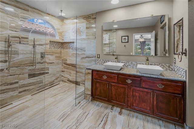 bathroom featuring marble finish floor, a tile shower, and a sink
