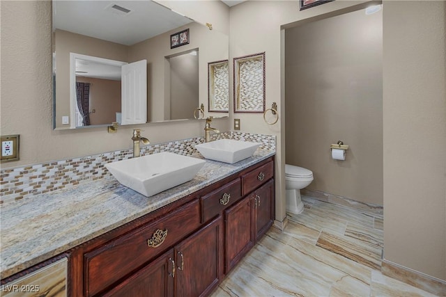 full bath featuring toilet, visible vents, a sink, and double vanity