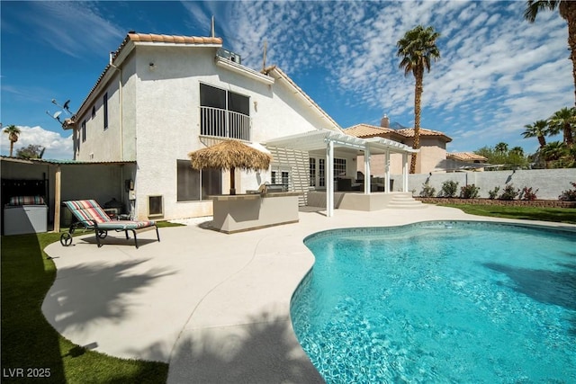 rear view of house featuring fence, a patio, stucco siding, exterior kitchen, and a pergola