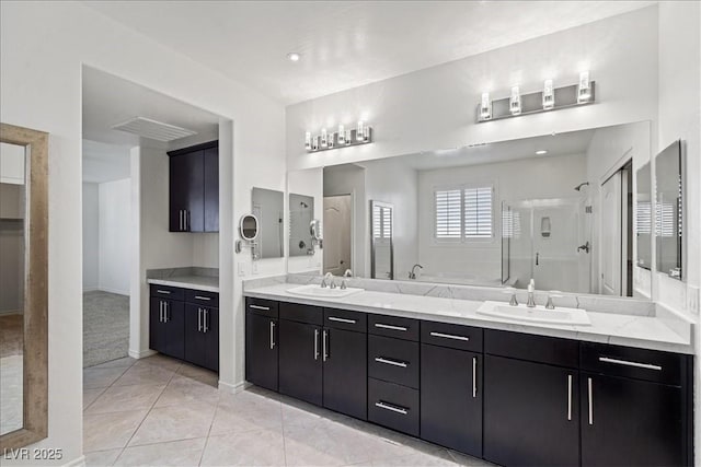bathroom featuring a sink, double vanity, a walk in shower, and baseboards