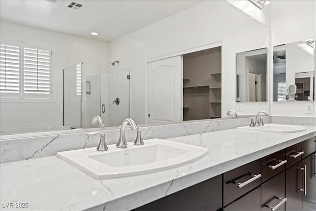 full bathroom with double vanity, visible vents, a stall shower, and a sink