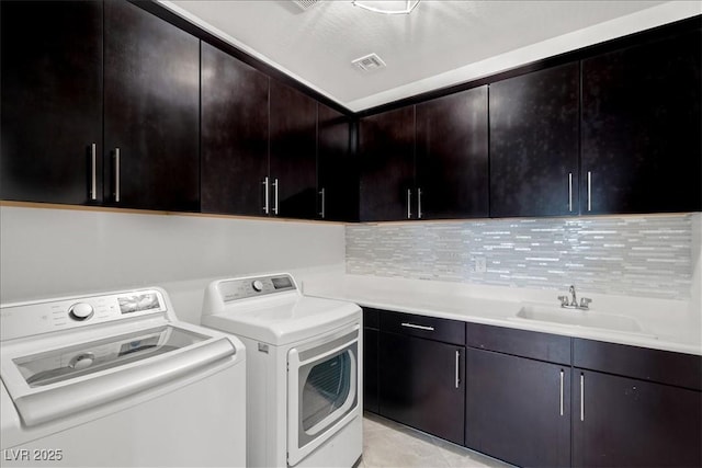clothes washing area featuring cabinet space, washer and clothes dryer, and a sink