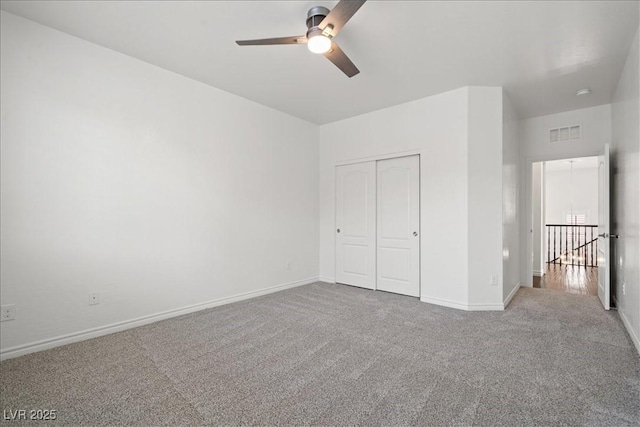 unfurnished bedroom featuring a closet, visible vents, carpet floors, a ceiling fan, and baseboards