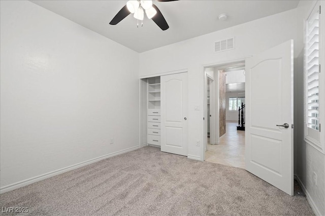 unfurnished bedroom featuring a closet, baseboards, ceiling fan, visible vents, and light colored carpet