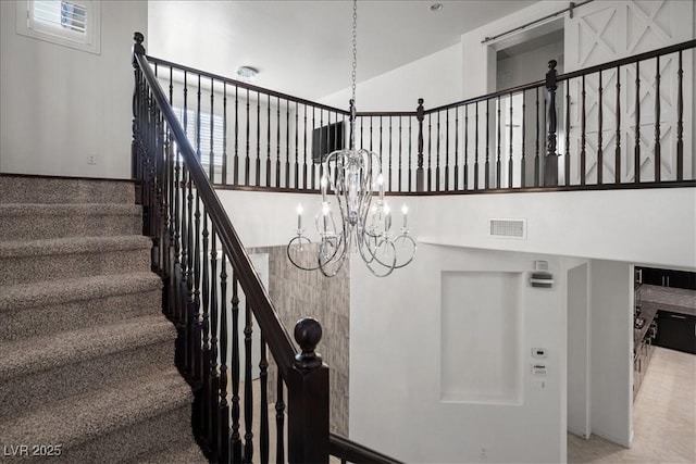 staircase featuring an inviting chandelier, plenty of natural light, and visible vents