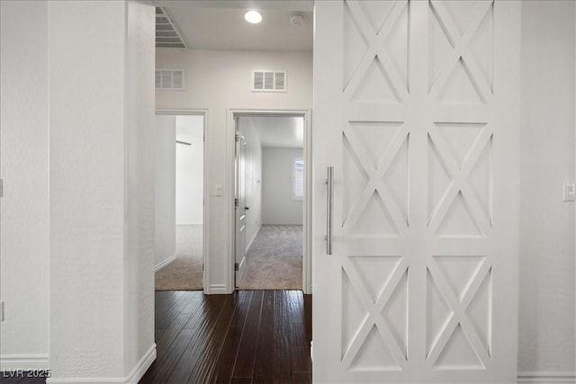 corridor featuring baseboards, visible vents, and dark wood-style floors