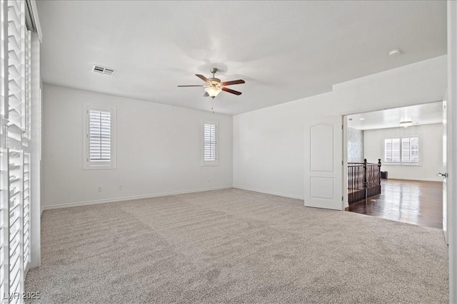empty room featuring a wealth of natural light, ceiling fan, visible vents, and carpet floors