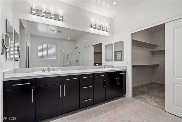 full bath with a shower stall, double vanity, a sink, and a walk in closet