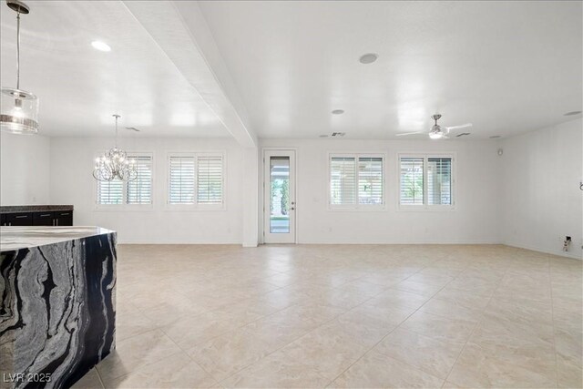 unfurnished living room featuring light tile patterned floors, baseboards, and ceiling fan with notable chandelier