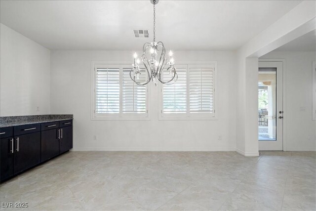 unfurnished dining area with a chandelier and baseboards