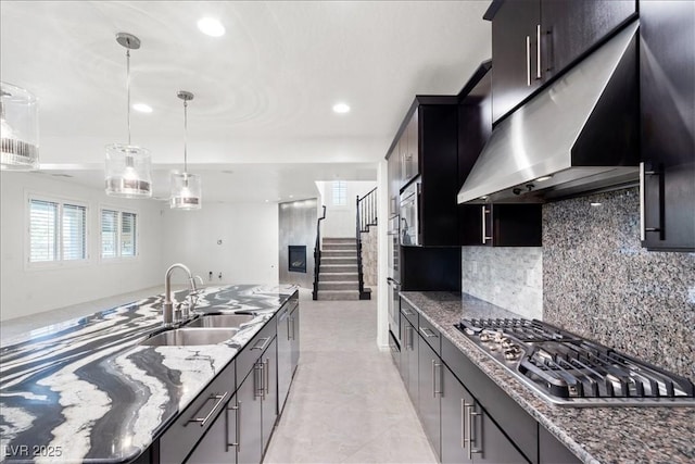 kitchen featuring under cabinet range hood, a sink, backsplash, stainless steel appliances, and dark stone counters