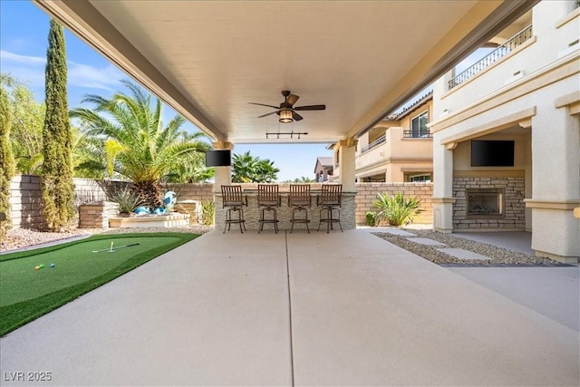 view of patio featuring a fenced backyard, ceiling fan, and outdoor dry bar