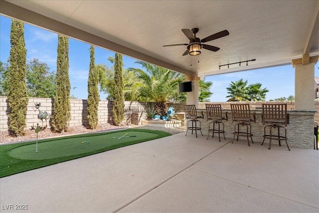 view of patio featuring ceiling fan, a fenced backyard, and outdoor dry bar