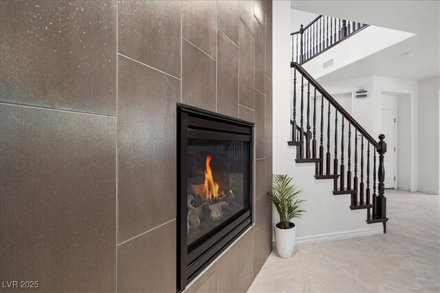 stairs with a glass covered fireplace and baseboards