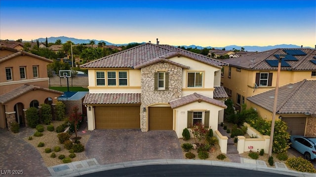 view of front of house featuring a tile roof, stucco siding, an attached garage, and decorative driveway