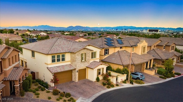mediterranean / spanish home with driveway, an attached garage, stucco siding, a residential view, and a tile roof