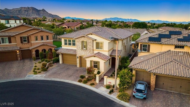 mediterranean / spanish-style home featuring a mountain view, a tiled roof, driveway, and a residential view
