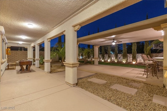 patio at night featuring ceiling fan, fence, and outdoor dining space