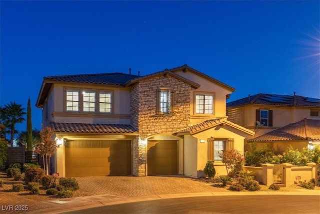 view of front of property featuring decorative driveway, an attached garage, stucco siding, a tile roof, and stone siding