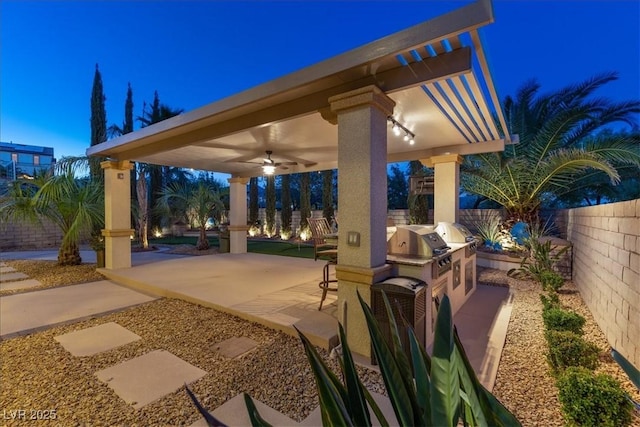 view of patio / terrace with a fenced backyard, ceiling fan, and an outdoor kitchen