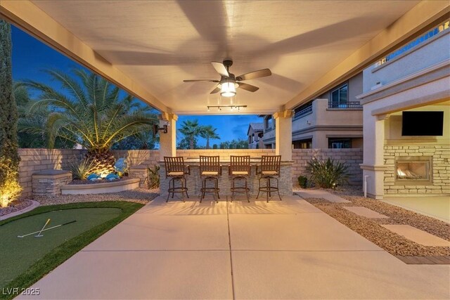 view of patio featuring a putting green, a fenced backyard, and a ceiling fan