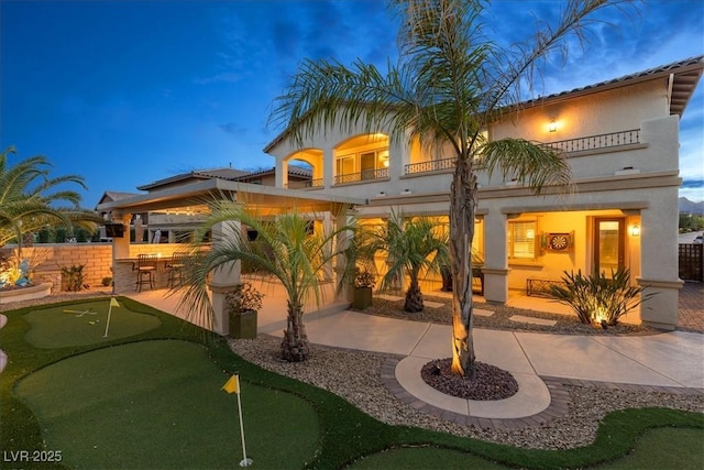 rear view of house featuring a balcony, a patio, and fence