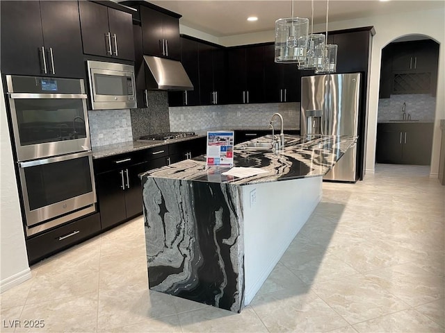 kitchen with stainless steel appliances, a sink, under cabinet range hood, decorative backsplash, and recessed lighting