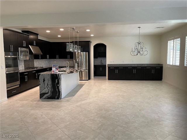 kitchen with stainless steel appliances, dark cabinets, under cabinet range hood, tasteful backsplash, and recessed lighting