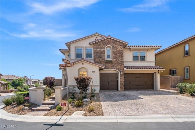 mediterranean / spanish home with a tiled roof, fence, decorative driveway, a garage, and stucco siding