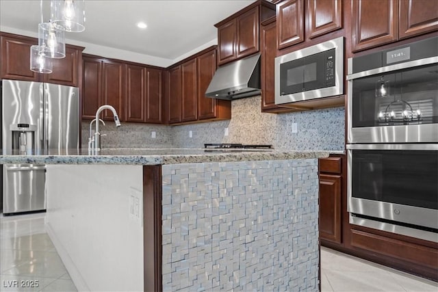 kitchen with light tile patterned floors, light stone counters, stainless steel appliances, and extractor fan