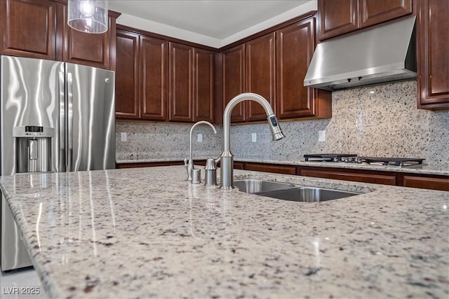 kitchen with under cabinet range hood, tasteful backsplash, a sink, and light stone counters