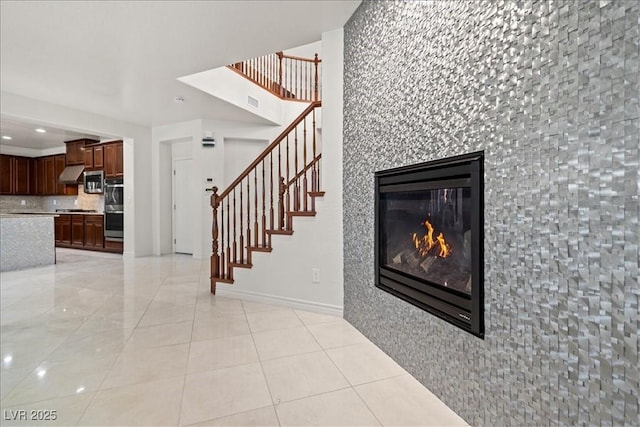 stairway featuring recessed lighting, baseboards, a glass covered fireplace, and tile patterned floors