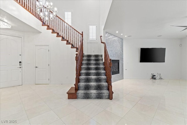 staircase with baseboards, tile patterned flooring, a chandelier, and a high ceiling