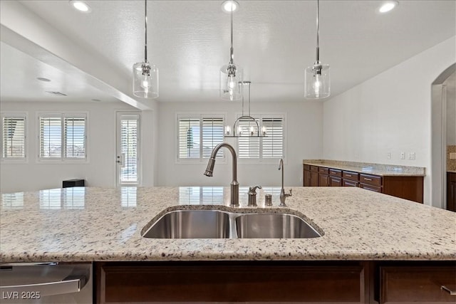 kitchen with dishwasher, light stone counters, a healthy amount of sunlight, and a sink