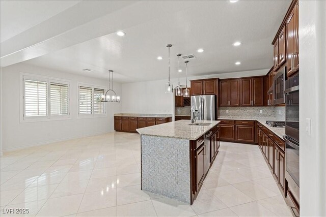 kitchen featuring a sink, a spacious island, backsplash, a notable chandelier, and appliances with stainless steel finishes