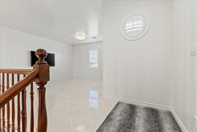 corridor featuring baseboards and light tile patterned floors