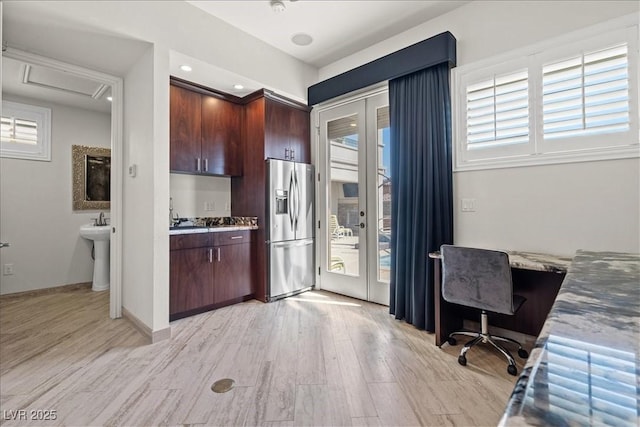 kitchen with dark brown cabinetry, stainless steel fridge with ice dispenser, light countertops, and light wood-style floors
