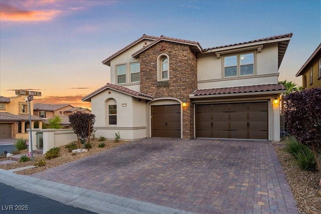 view of front facade with an attached garage, stone siding, stucco siding, a tile roof, and driveway