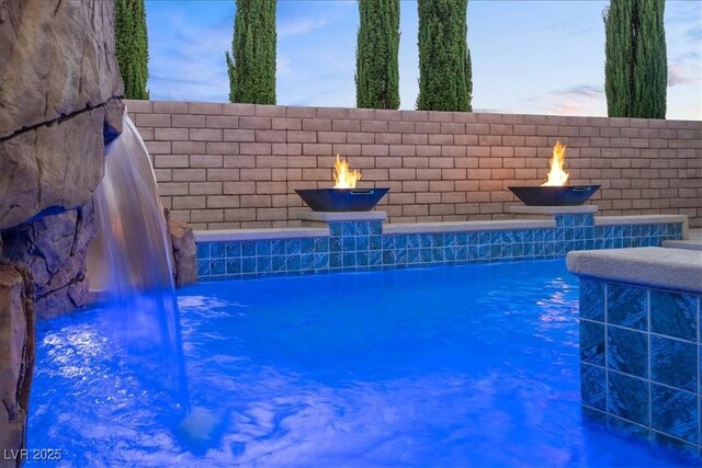 view of swimming pool featuring a fenced in pool and a fire pit