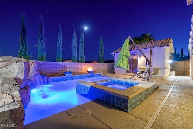 pool at night featuring an in ground hot tub, a fenced in pool, a fenced backyard, and a patio