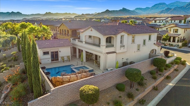 rear view of house with a fenced backyard, stucco siding, a mountain view, and a balcony