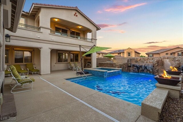 view of pool with a patio area, a pool with connected hot tub, a fire pit, and a fenced backyard