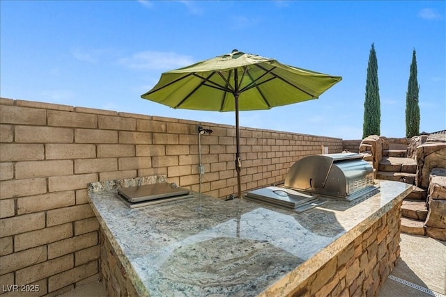view of patio featuring fence, an outdoor kitchen, and a grill
