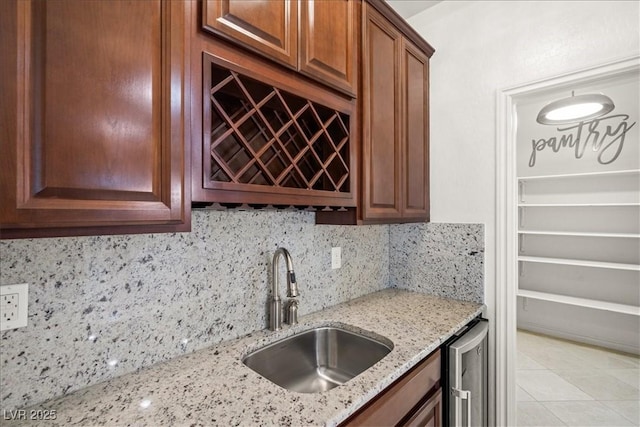 kitchen with a sink, light stone countertops, backsplash, light tile patterned flooring, and wine cooler