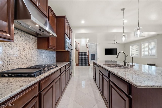 kitchen with under cabinet range hood, a sink, open floor plan, backsplash, and stainless steel appliances