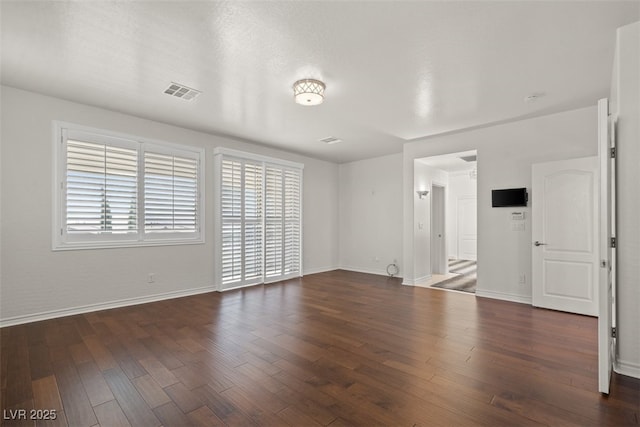 unfurnished living room with baseboards, visible vents, and wood finished floors