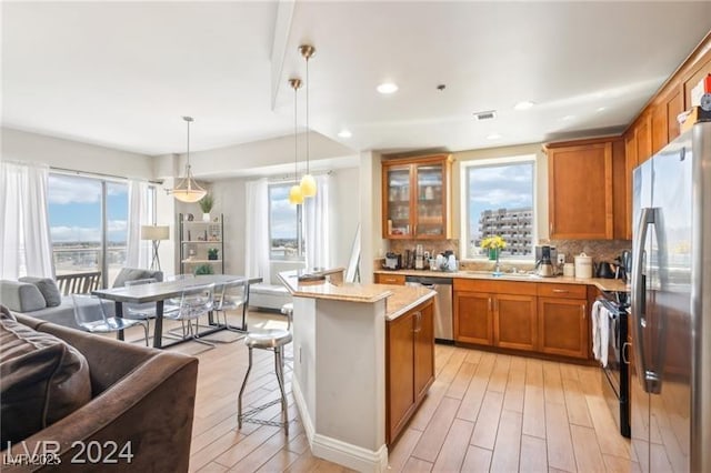 8255 Las Vegas Blvd Unit 713, Las Vegas, NV 89123 - kitchen featuring brown cabinetry, appliances with stainless steel finishes, open floor plan, glass insert cabinets, and light wood-style floors